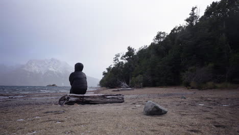 lonely and sad person sitting on log on empty exotic beach