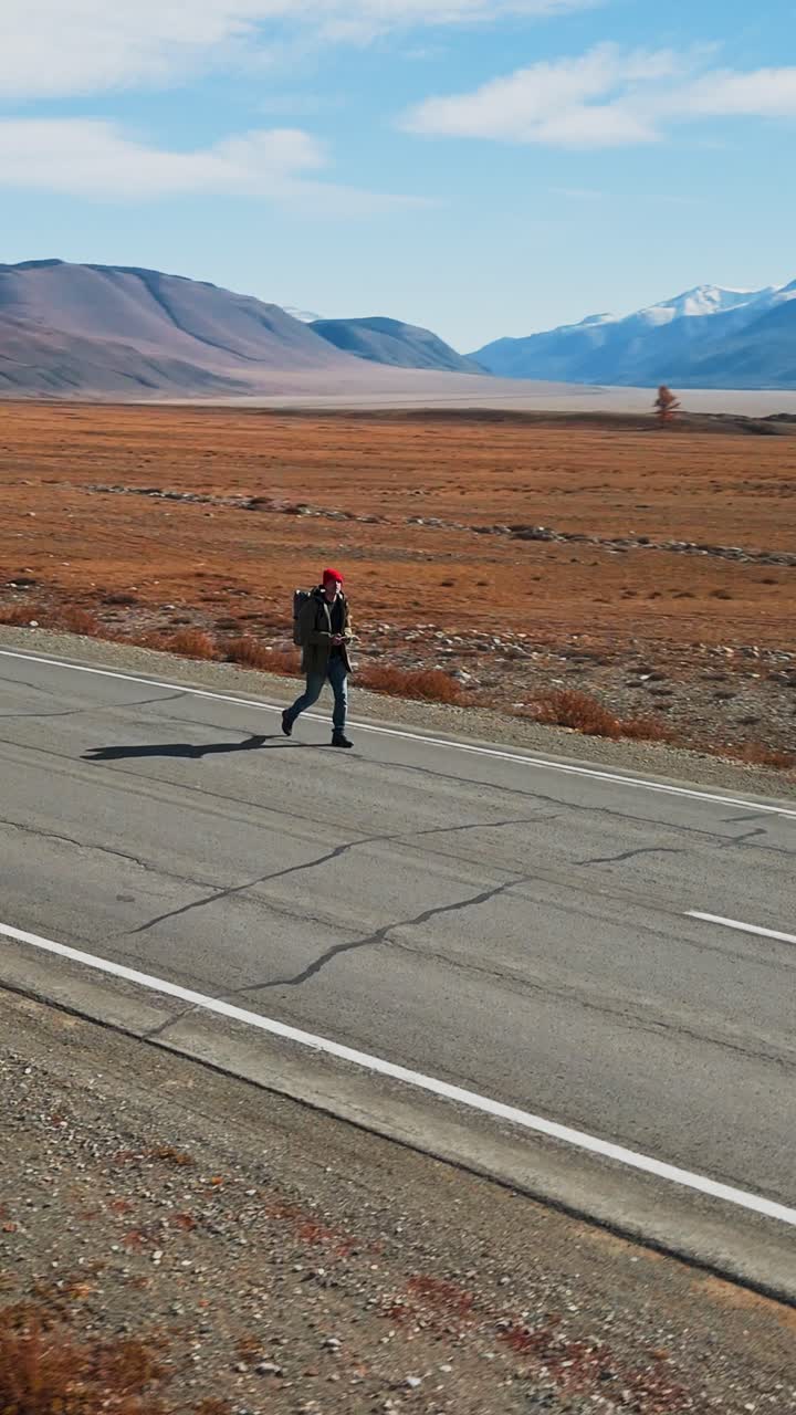 Viaggiatore solitario che cammina su una strada deserta in un vasto paesaggio montano