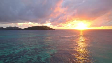 vibrant golden sunset over water and coral reef, yasawa, fiji, parallax shot