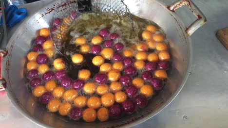 cooking quail candy eggs or turtle eggs sweets in big pan with hot oil, thai traditional dessert snack made from cassava flour (tapioca starch) and sweet potato at the market. 4k footage.