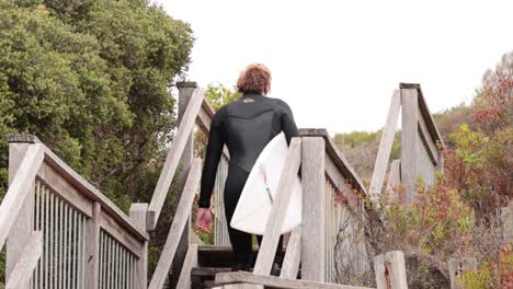 surfer climbs stairs with surfboard in hand