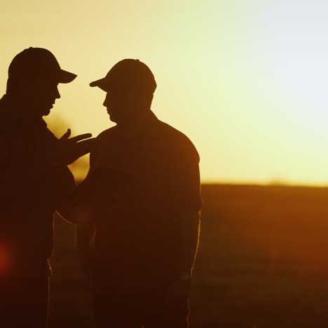 two farmer workers talk in the field and use a tablet