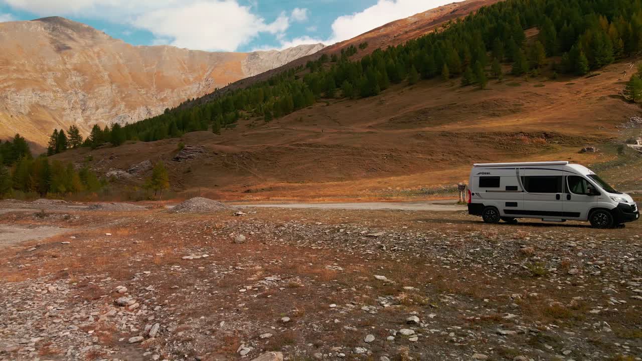 Flowing River With Camper Van Parked Against Scenic Mountainscape During Autumn Season