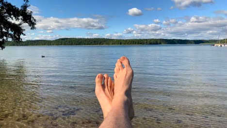 First-person-perspective-view-of-relaxing-feet-on-the-lakeshore