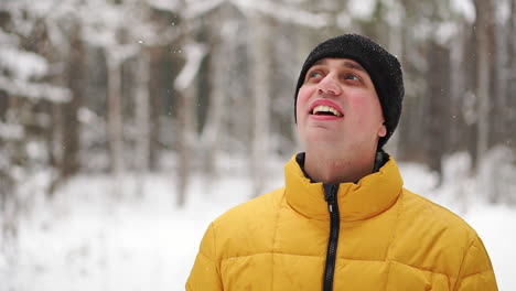 Ein-Mann-In-Einer-Gelben-Jacke-Betrachtet-Den-Schnee-Im-Winter-Im-Wald-Und-Lächelt-In-Zeitlupe