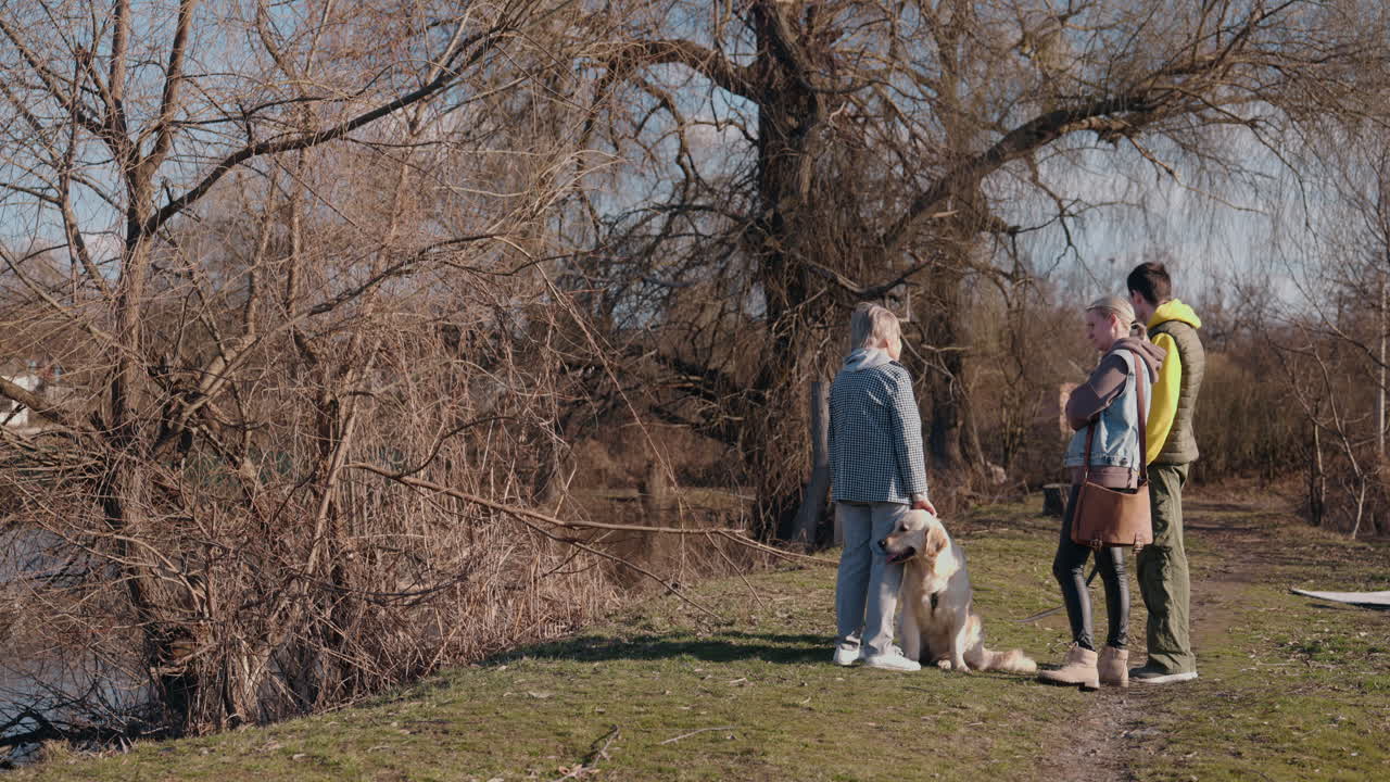 가족 들 이 호수 근처 에 있는 개 와 함께 하루 를 즐기고 있다