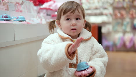 linda niña de 3 años jugando presionando el botón de un timbre de juguete en un centro comercial