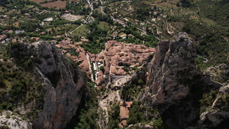 The-village-of-Moustiers-Sainte-Marie,-seen-from-above-the-limestone-cliff