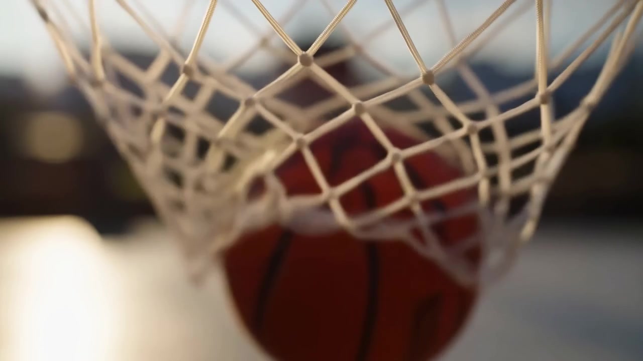 Primo piano di una rete da basket con un pallone, in un campo sportivo all'aperto, con la rete in primo piano, con accenti bianchi e rossi
