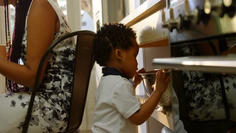 side view of cute little black son looking in colander in kitchen of comfortable home 4k