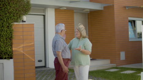 una pareja de ancianos de pie al aire libre y discutiendo la compra de una casa nueva