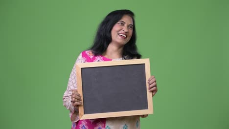 madura feliz hermosa mujer india mostrando la pizarra mientras piensa