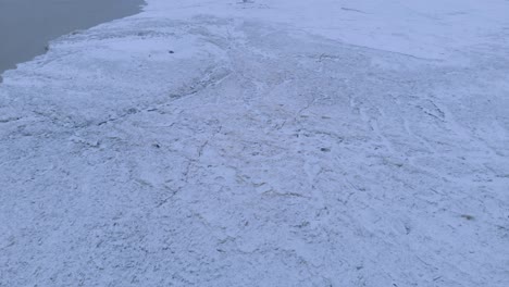 areal shot rising away from an ice dam on a winter river
