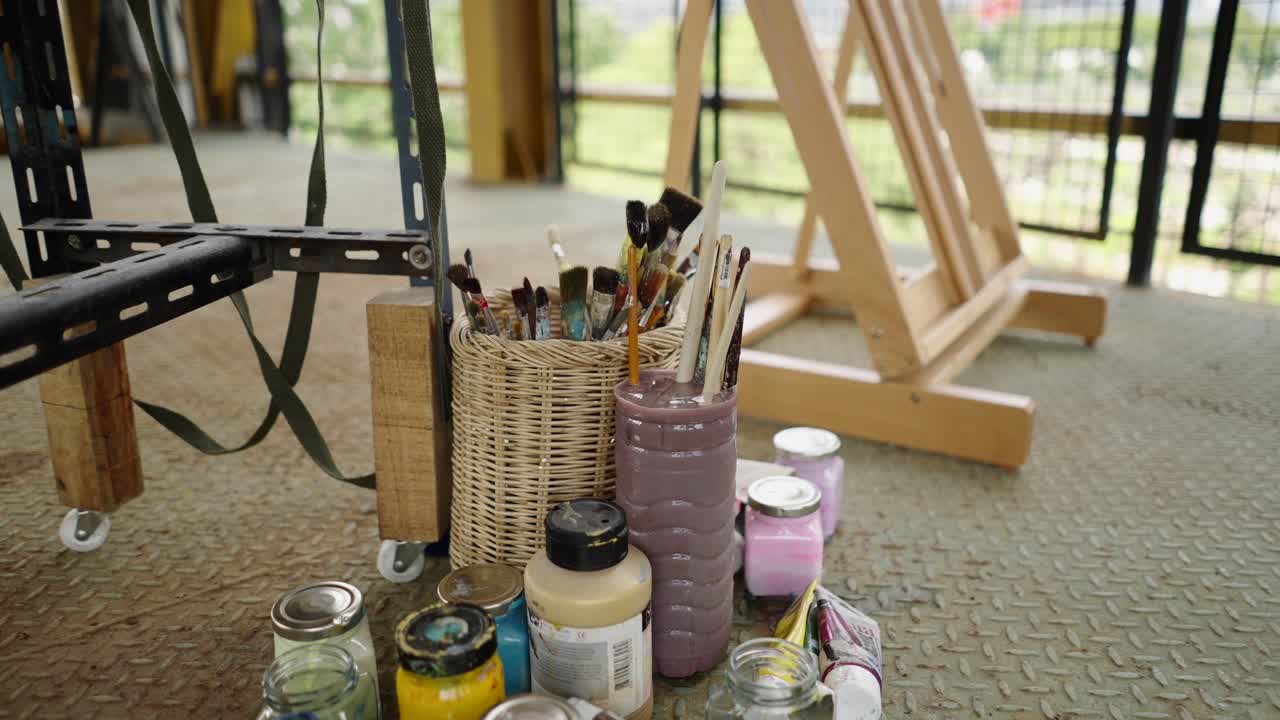 Art supplies, including brushes, paints, and an easel, set up in a creative studio space
