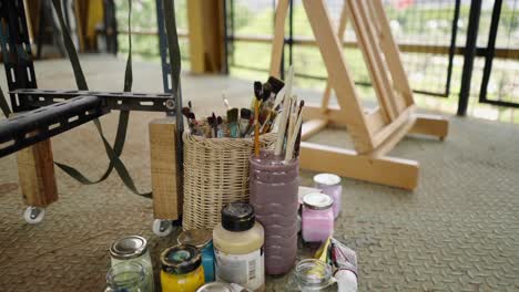 art supplies, including brushes, paints, and an easel, set up in a creative studio space
