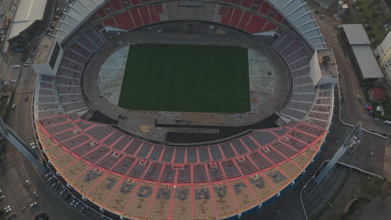 Riprese aeree che scendono lentamente sullo Stadio Nazionale Rajamangala, mostrando le tribune vuote e il campo verde a Bangkok, Thailandia