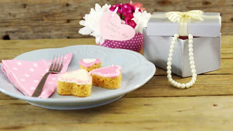 open gift box with flower vase and heart shape cookies