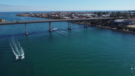 aerial view of speedboat passing with bridge in background