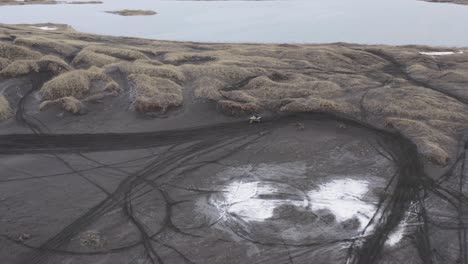 Motorcycle-rider-making-turn-on-sandy-track-in-rugged-dunes,-aerial