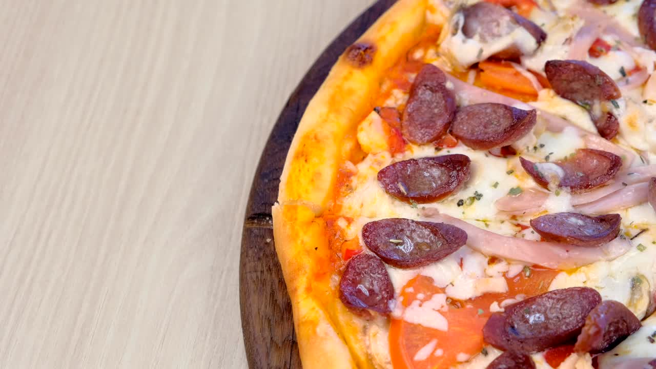Metà pizza con salsiccia affumicata, prosciutto e formaggio. Vista ravvicinata dall'alto