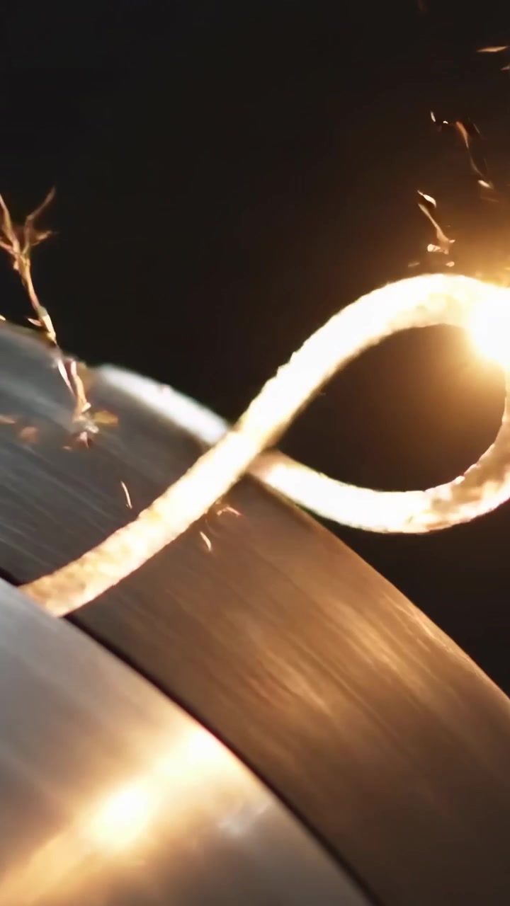 Vertical video: Heating thin metal strip by arc at tip, forming loop on workshop drum and cooling