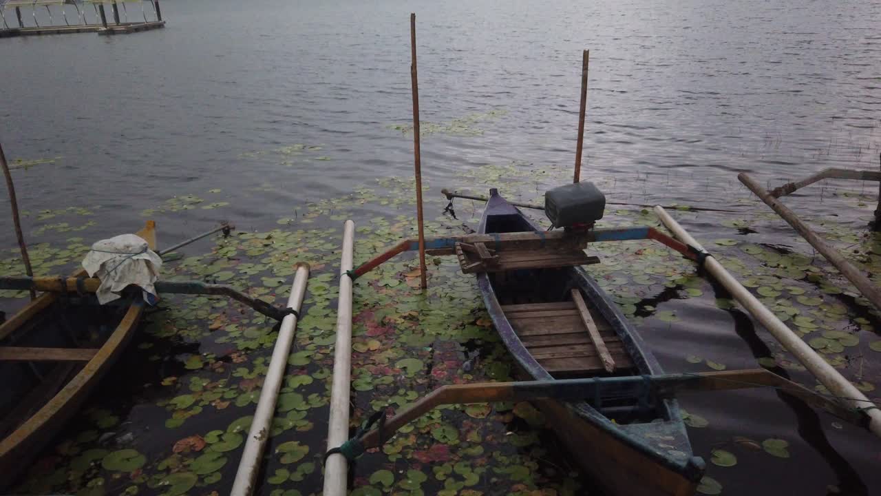 las canoas en su barco se deslizan en el lago beratan en bali, indonesia rodeadas de lirios