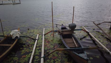 Canoes-in-their-boat-slips-at-Beratan-Lake-in-Bali,-Indonesia-surrounded-by-lily-pads