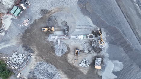 Tiro-De-Dron-De-Gato-Bob,-Camión-Volquete-Y-Excavadora-Minera-Moviendo-Rocas,-Con-Cinta-Transportadora-Clasificando-Rocas-Con-Escombros-En-Pilas-En-La-Mina-De-Cantera