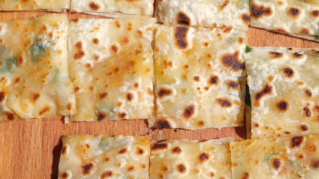 Primo piano di focacce quadrate appena sfornate su un tagliere di legno.