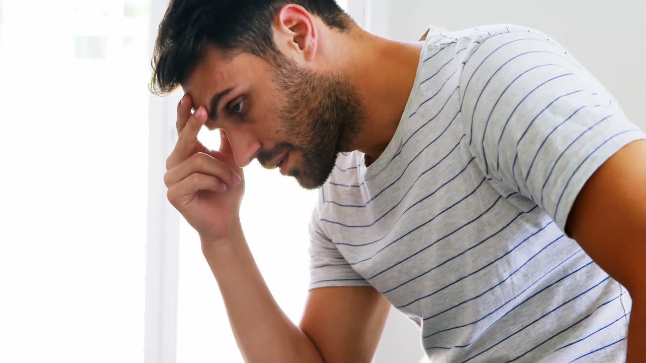 hombre preocupado sentado en la cama en el dormitorio