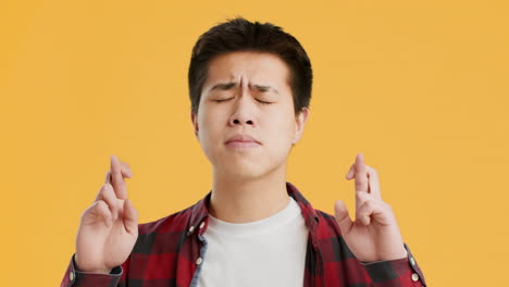 asian man with fingers crossed