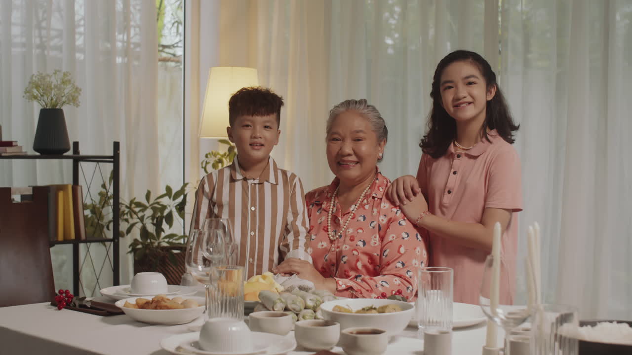 Portrait of Siblings Cuddling Grandmother at Festive Table