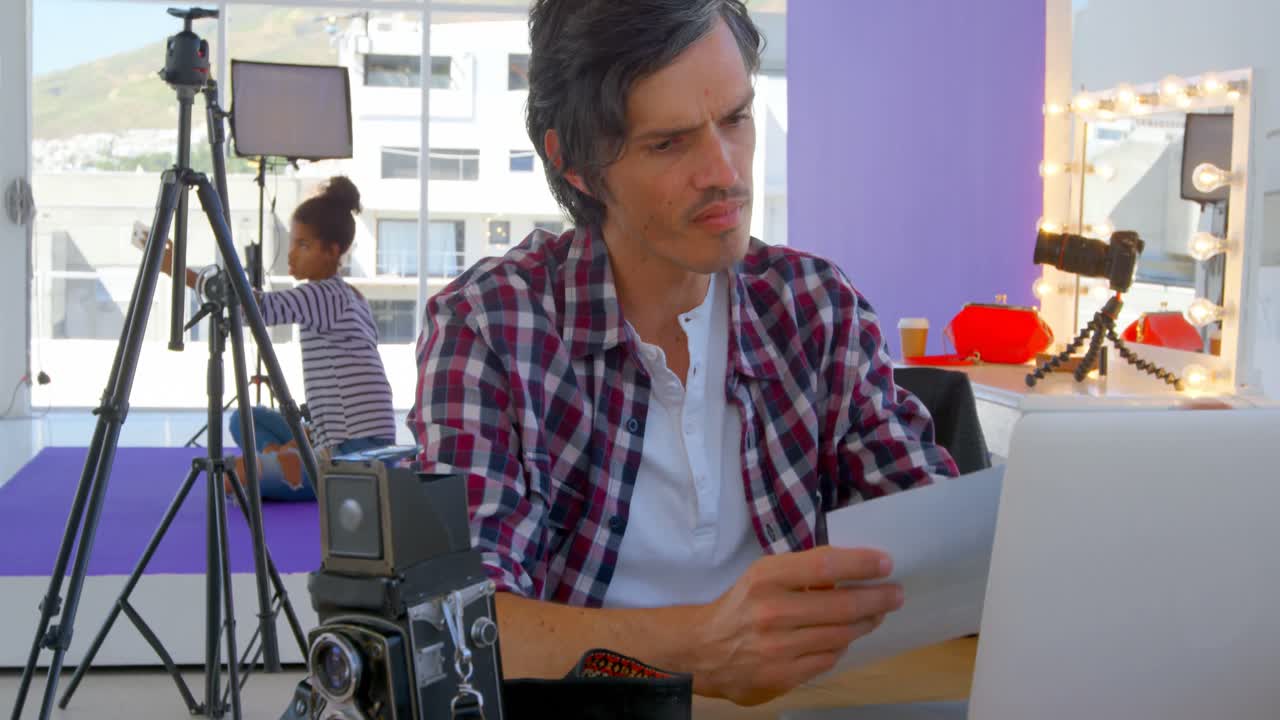 fotógrafo masculino usando una computadora portátil en un estudio fotográfico 4k