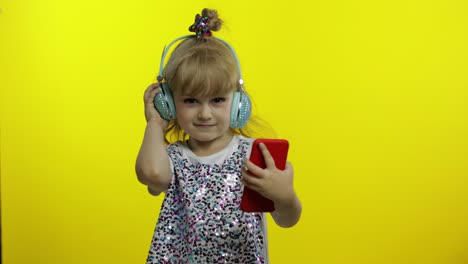 El-Niño-Baila-Con-El-Teléfono-Inteligente,-Escuchando-Música-Con-Auriculares.-Niña-Pequeña-Bailando,-Teniendo-Cariño