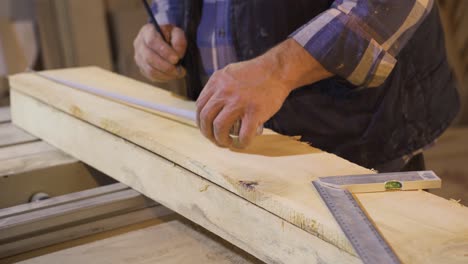 close-up of crumpled carpenter hands measuring wood with meter.