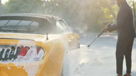 man washing a yellow convertible car