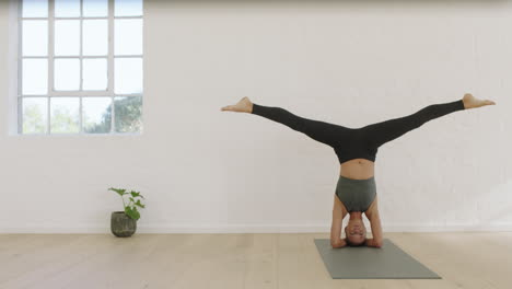 una mujer de yoga saludable practicando divisiones de cabeza posando disfrutando de un estilo de vida fitness haciendo ejercicio en el estudio estirando un hermoso entrenamiento corporal en una colchoneta de ejercicios