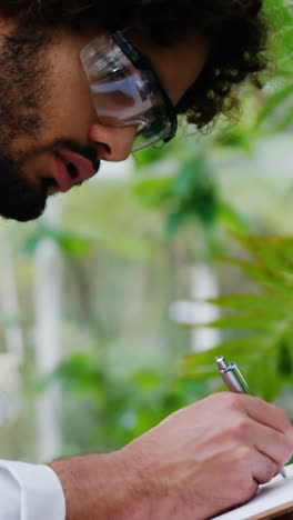 man taking notes of plants on clipboard