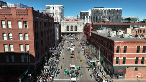 Aerial-view-of-a-Saint-Patrick's-Day-parade-making-its-way-through-Denver's-downtown-skyscrapers