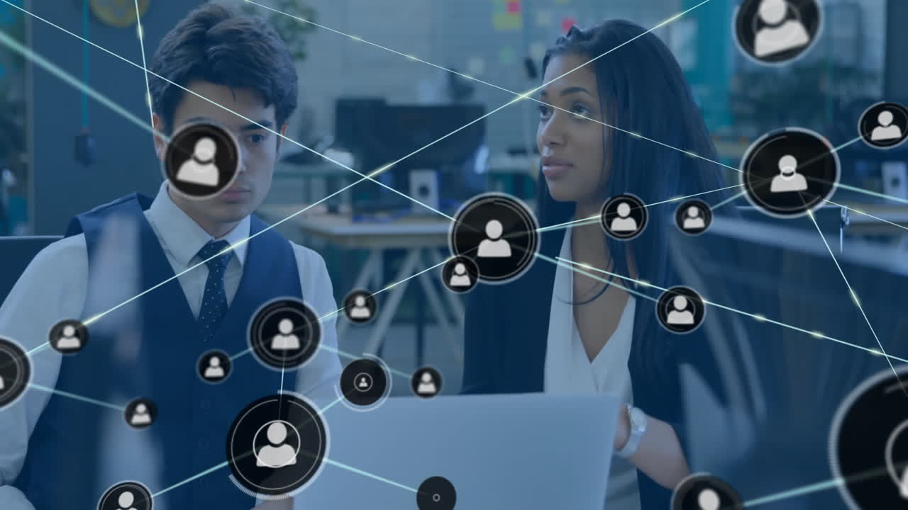 Two coworkers collaborating in tech office, streaming network icons across laptop screen