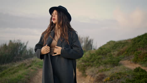 girl walking dirt road in elegant hat. confident woman going on rural path.