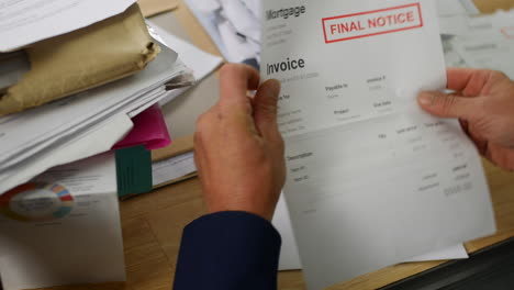 a man opening a stack of bills and letters with final notice for mortgage debts