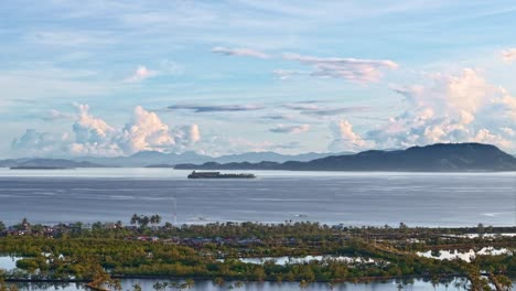 timelapse of morning light over calm waters, clouds drifting across the sky, serene and peaceful strait view as barges cross in front of mountains, aerial tracking to the right