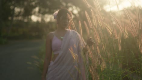 woman in a pink dress enjoying the golden hour amidst tall grass, soft focus, backlit by the sun