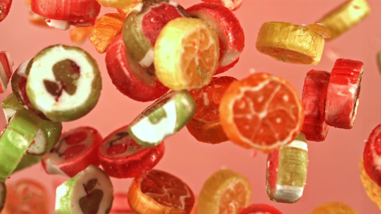 Caramelle alla frutta dolci e colorate sospese su uno sfondo rosa
