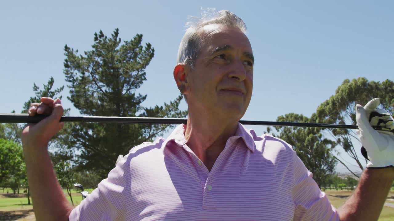 Retrato de un hombre mayor caucásico con un palo de golf sonriendo en el campo de golf en un día soleado y luminoso.
