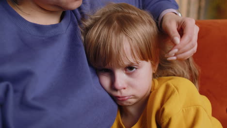 closeup of sad girl kid is crying and lying on mother at home violence against children in family