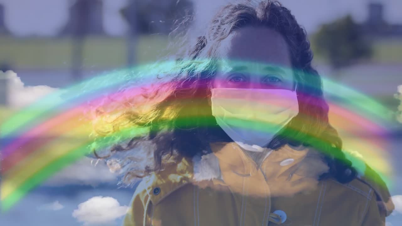 얼굴 마스크를 착용 한 여성에 대한 무지개와 파란 하늘