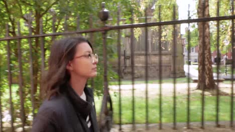 Close-Profile-Shot-of-a-Young-Woman-Walking-Along-a-Church-Lane