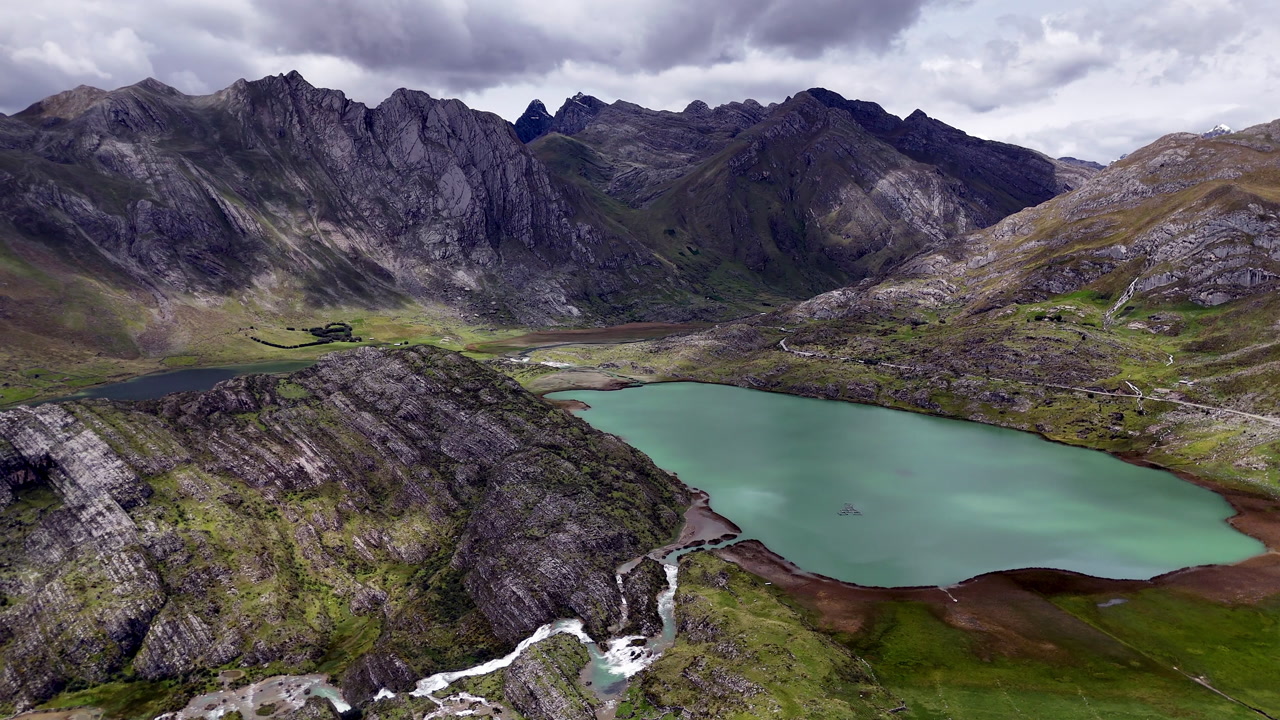 Scenic Andes mountain lake in Peru with turquoise water, rugged cliffs, and dramatic peaks under cloudy sky, pristine nature and breathtaking highland landscape